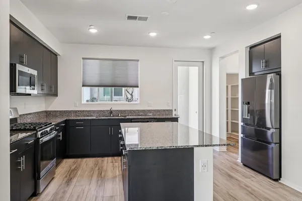 a kitchen with granite countertop a refrigerator stove top oven and sink