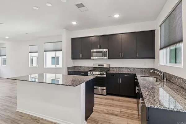 a kitchen with stainless steel appliances granite countertop a sink stove microwave and refrigerator