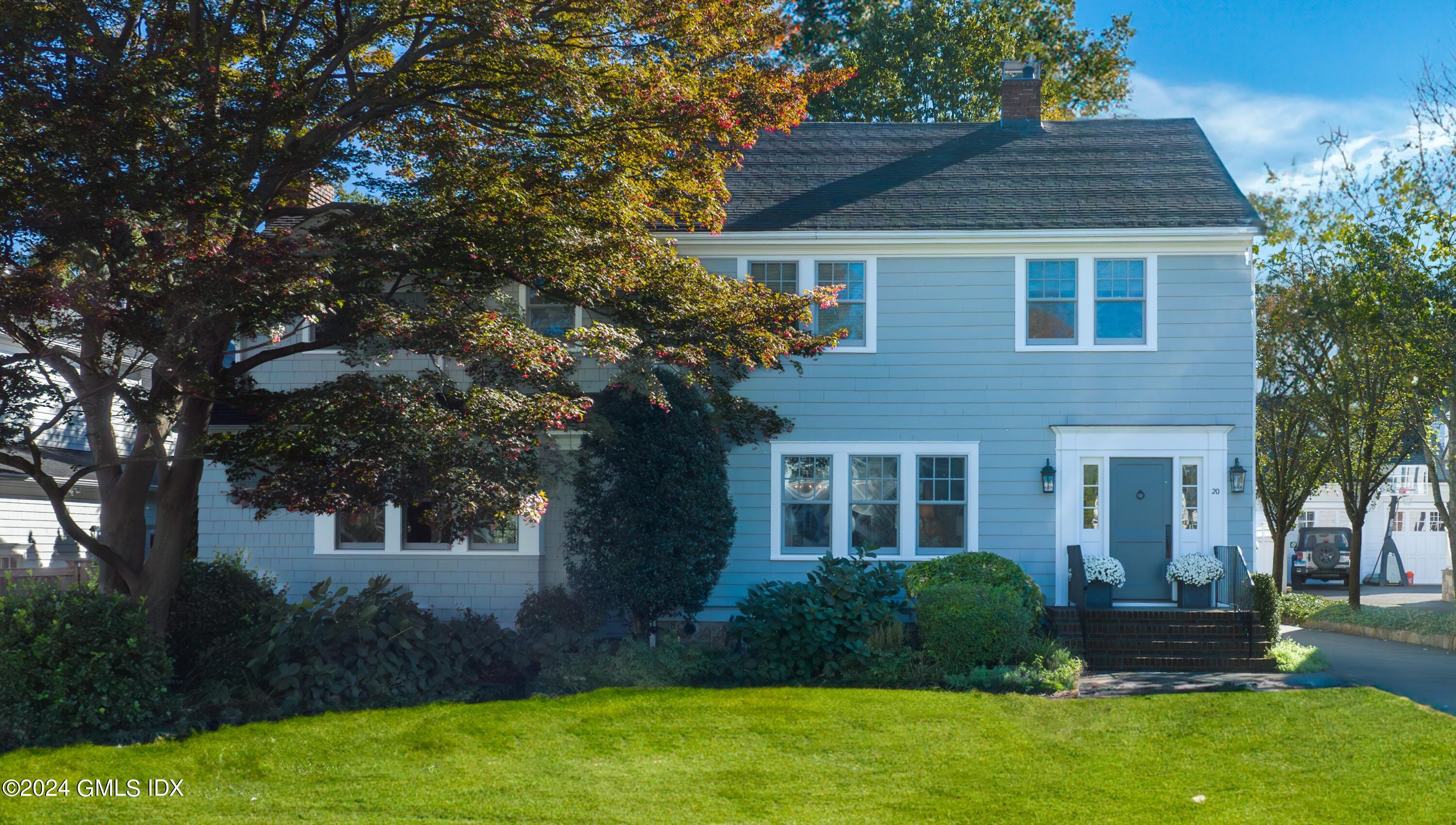 a front view of a house with a yard and trees