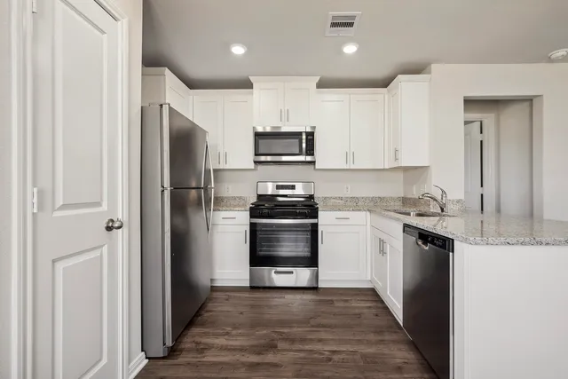 a kitchen with granite countertop white cabinets and stainless steel appliances