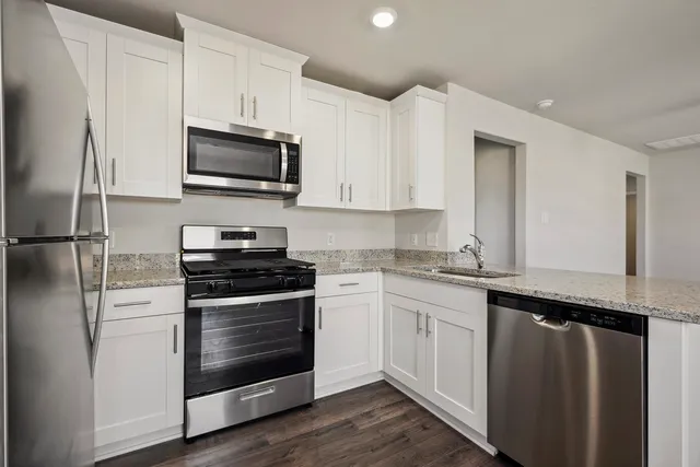 a kitchen with stainless steel appliances granite countertop a stove a refrigerator and a microwave