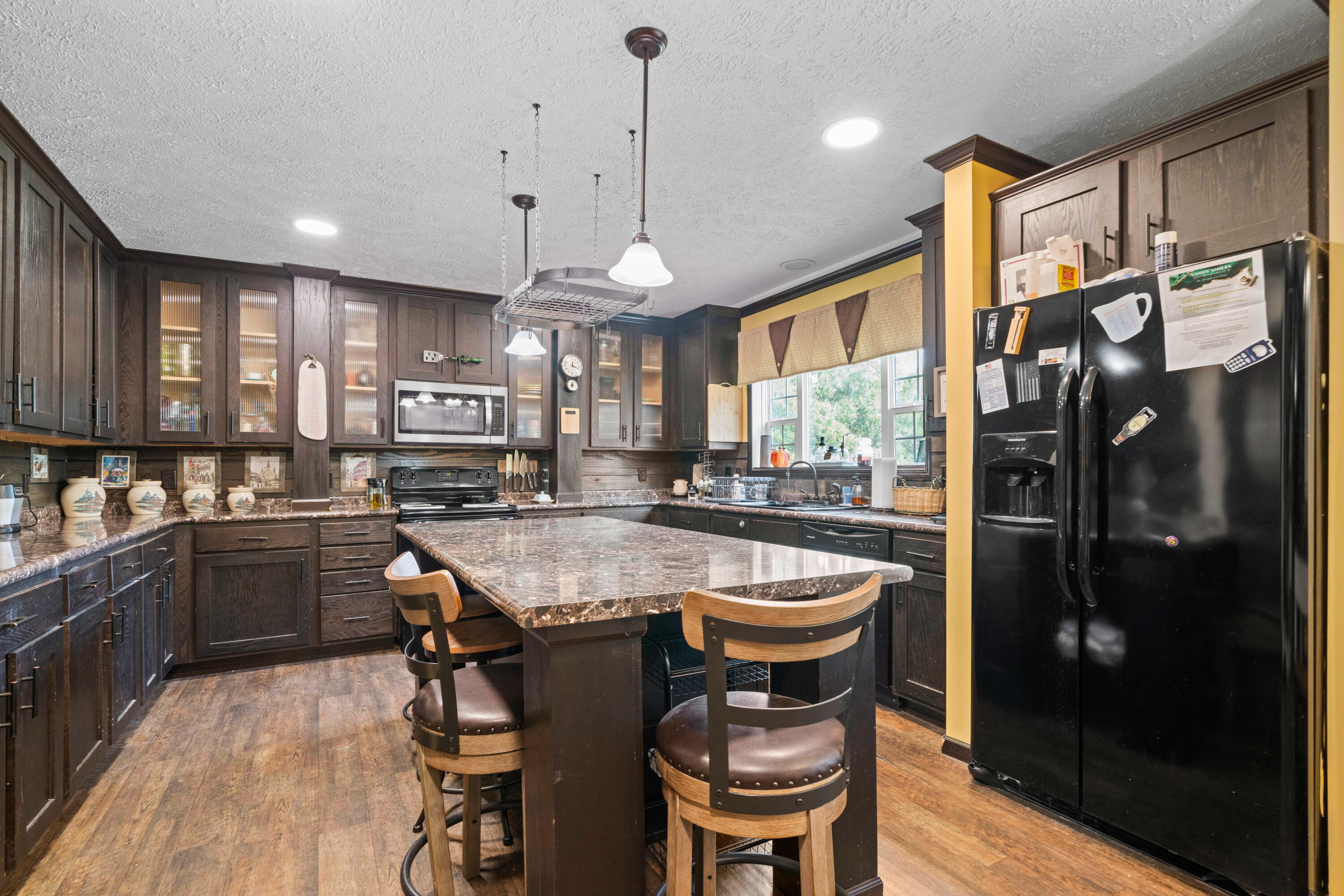 8320 Thames Road Baker, FL 32531 - Photo 25 of 48 a kitchen with stainless steel appliances granite countertop a kitchen island a stove a refrigerator a oven a sink a dining table and chairs with wooden floor