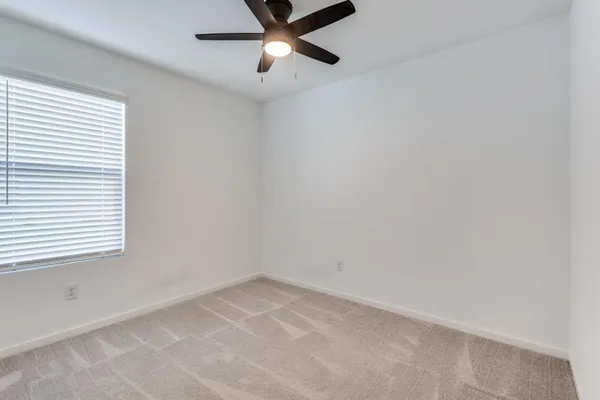 an empty room with a window and a fan