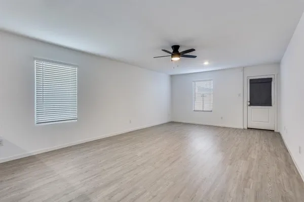 a view of an empty room with a window and a kitchen