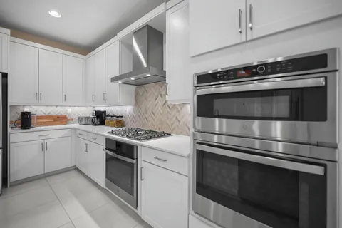 a kitchen with stainless steel appliances granite countertop a table chairs stove and refrigerator