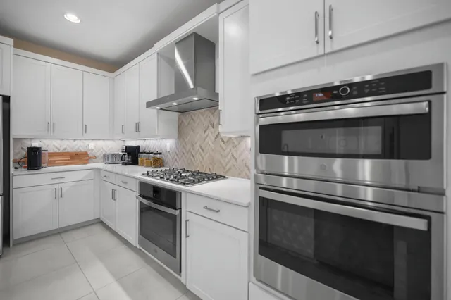 a kitchen with stainless steel appliances granite countertop a table chairs stove and refrigerator