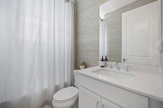 a bathroom with a sink a toilet and shower curtain
