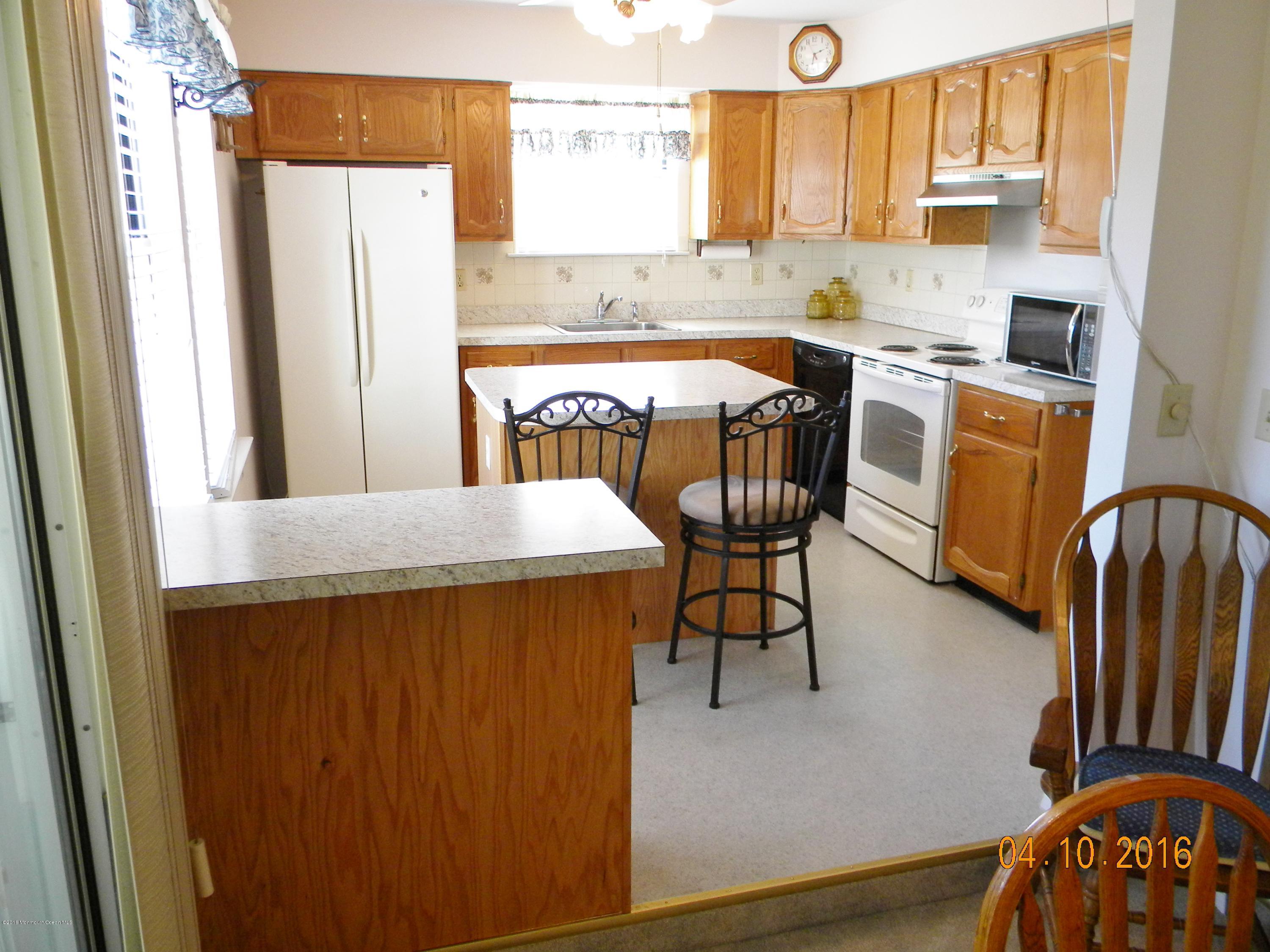 34A Ashley Road, Unit D Whiting, NJ 08759 - Photo 14 of 35 a kitchen with stainless steel appliances a refrigerator a stove a sink and white cabinets with wooden floor