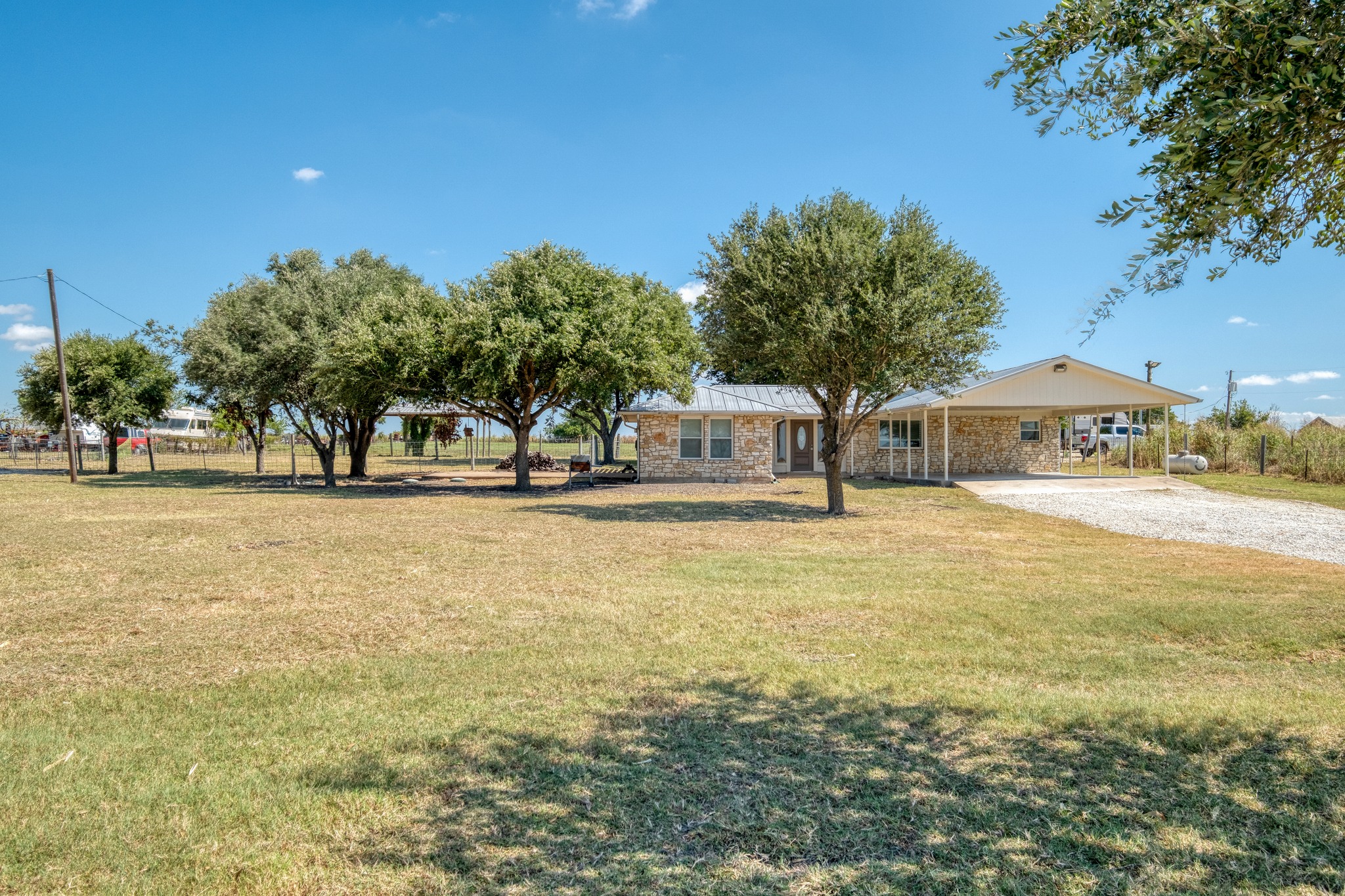 20960 Cameron Road Coupland, TX 78615 - Photo 1 of 21 Mature trees shade a limestone exterior with an attached carport on a sprawling lot.