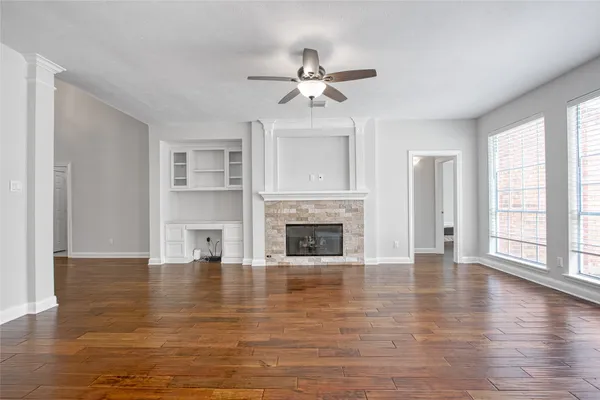 a view of a livingroom with wooden floor a ceiling fan and windows