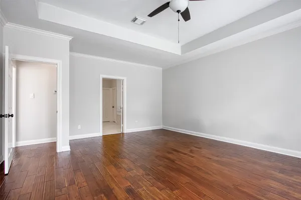 an empty room with wooden floor ceiling fan and windows