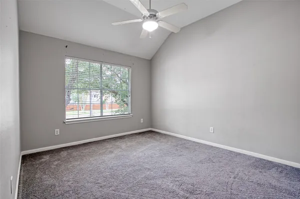 an empty room with a window and a fan