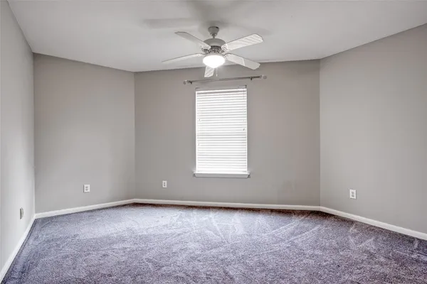 an empty room with a window and a ceiling fan