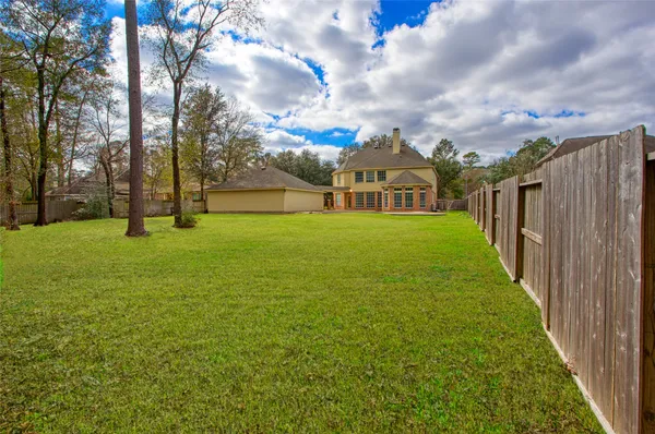 a view of a big yard with large trees and wooden fence