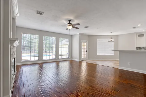 a view of an empty room with a window and wooden floor