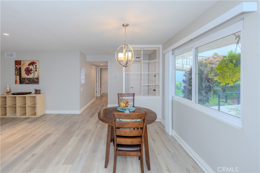 3379 Punta Alta, Unit B Laguna Woods, CA 92637 - Photo 7 of 25 a dining room with wooden floor a chandelier a wooden table and chairs