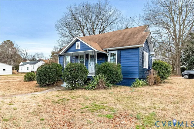 a view of a house with a yard and large tree