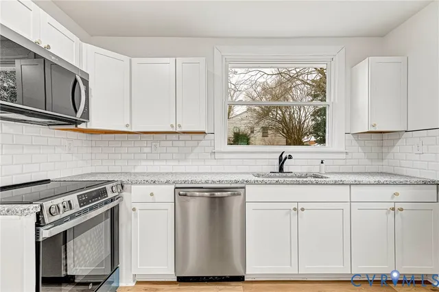 a kitchen with granite countertop white cabinets white stainless steel appliances and a sink