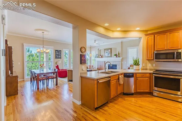 a kitchen with stainless steel appliances granite countertop a stove top oven a sink dishwasher a dining table and chairs with wooden floor