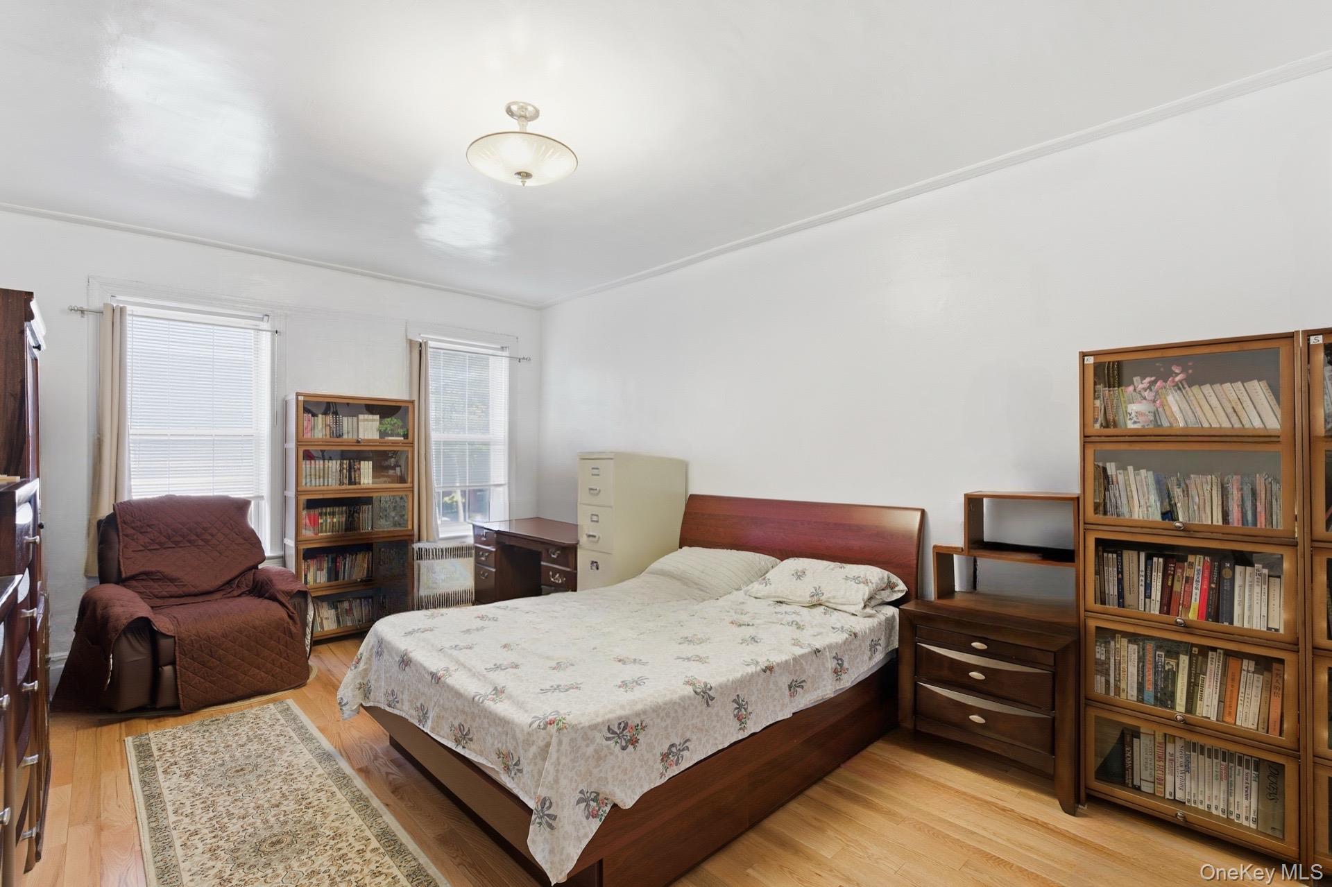 88-11 Elmhurst Avenue, Unit B6 Queens, NY 11373 - Photo 8 of 15 a bedroom with a bed a dresser and book shelf