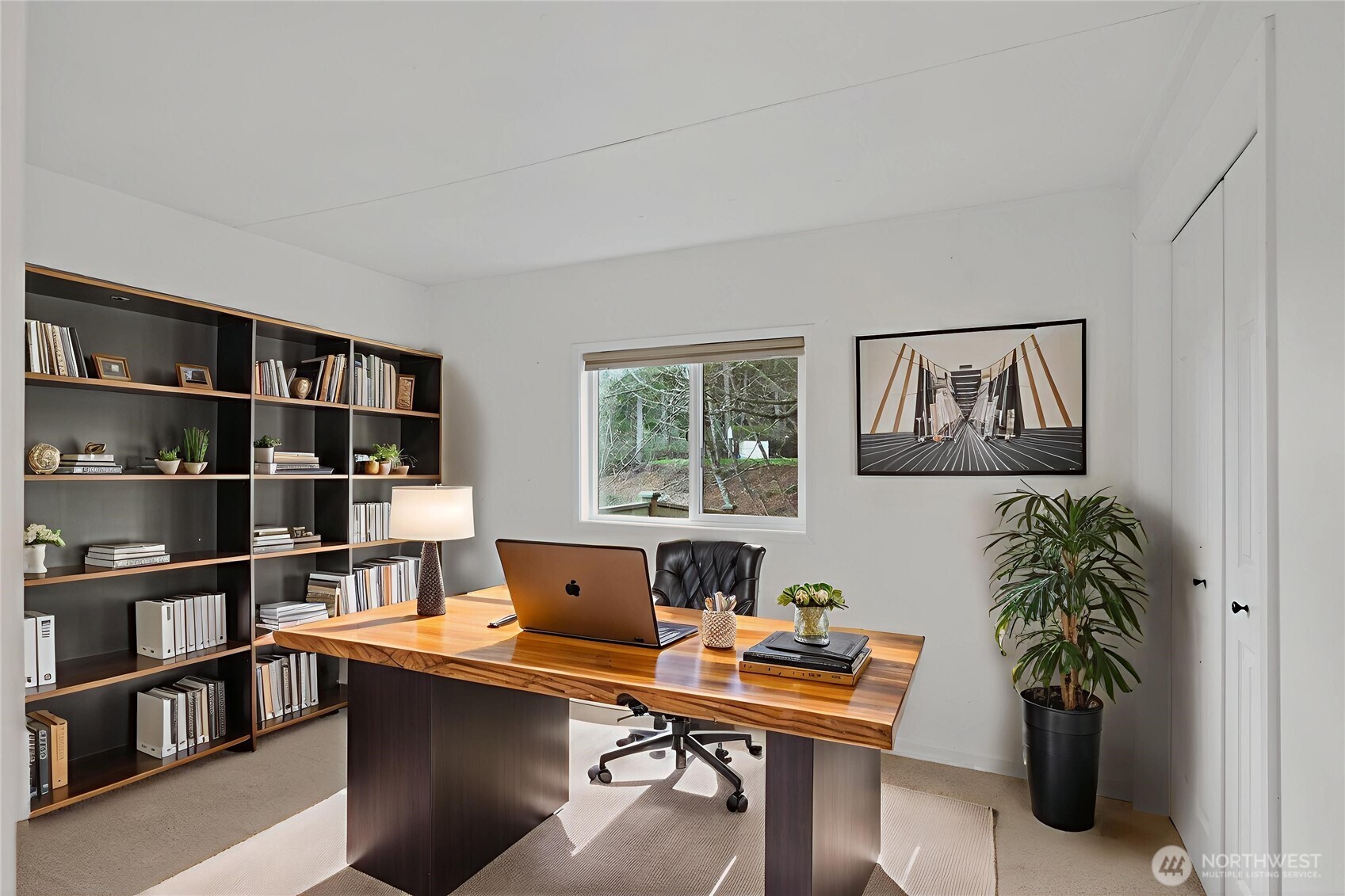 63 North Cross Island Road Camano Island, WA 98282 - Photo 16 of 23 a view of a workspace with a bookshelf and a potted plant on the wall