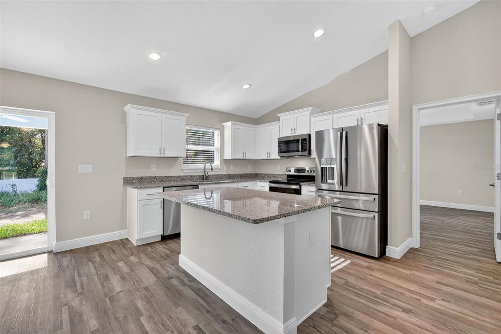 9 Chestnut Run Ocala, FL 34480 - Photo 12 of 17 a kitchen with stainless steel appliances granite countertop a refrigerator a stove top oven a sink and dishwasher with wooden floor