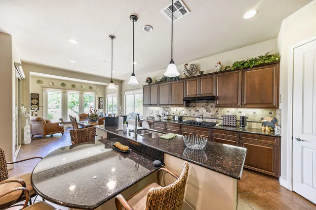 a kitchen with stainless steel appliances granite countertop a stove a sink a microwave a dining table and chairs