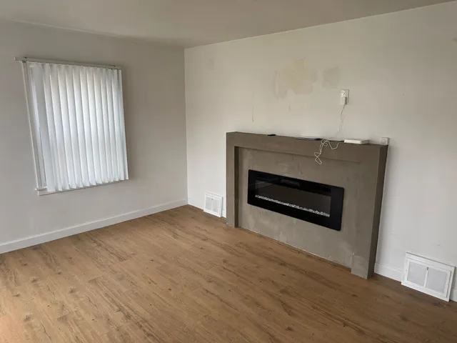 an empty room with wooden floor a fireplace and windows