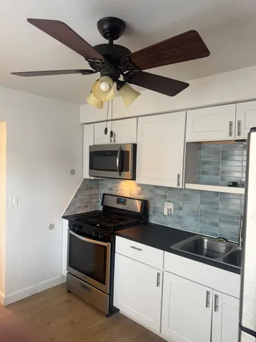 a kitchen with stainless steel appliances a stove and white cabinets