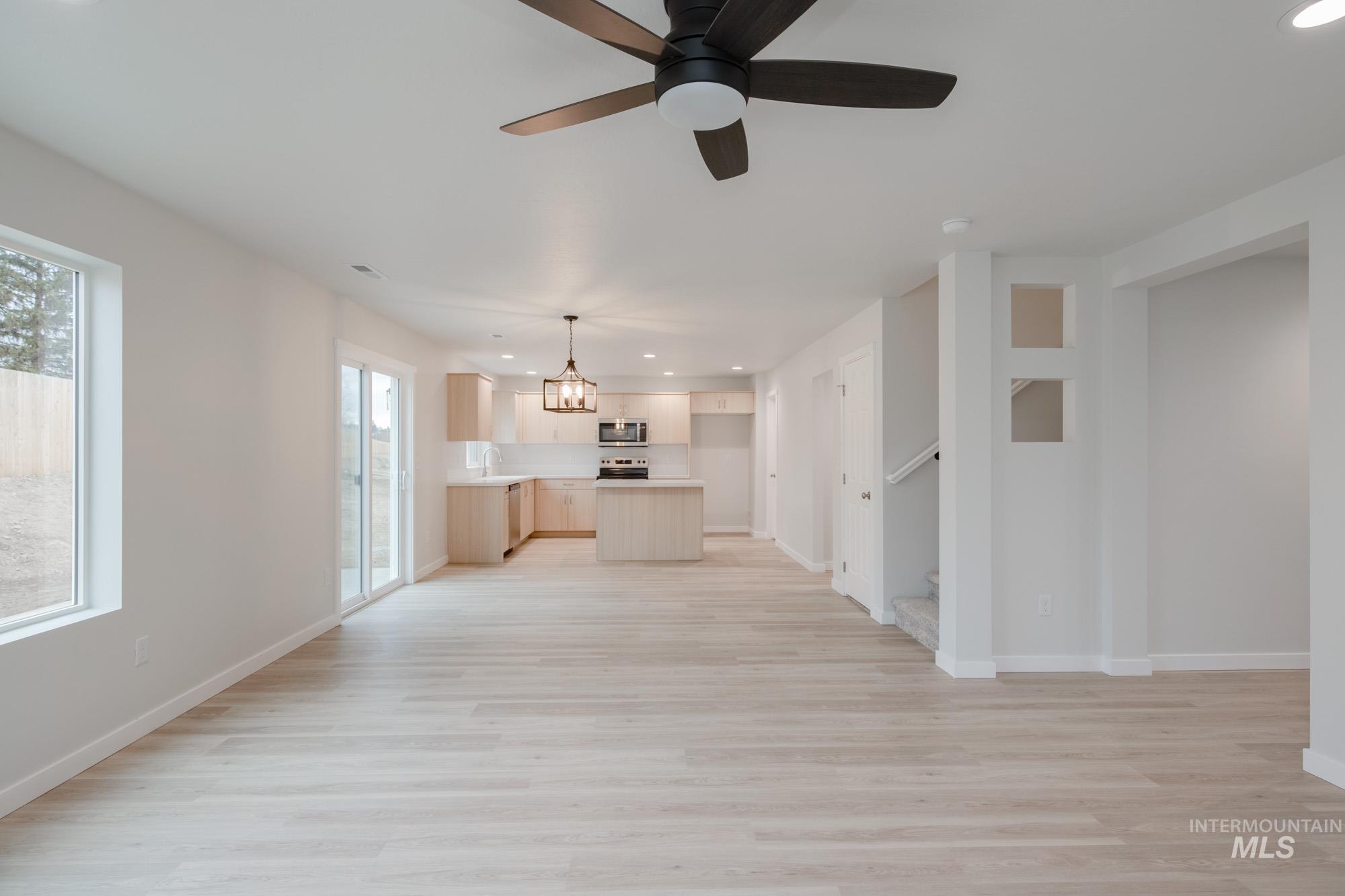 1472 Long Pond Street Middleton, ID 83644 - Photo 10 of 21 Unfurnished living room with recessed lighting, light wood-style flooring, a ceiling fan, a chandelier, and stairs