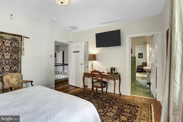 a bedroom with a bed a desk and chair with the wooden floor