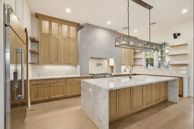a large kitchen with a sink a center island and stainless steel appliances