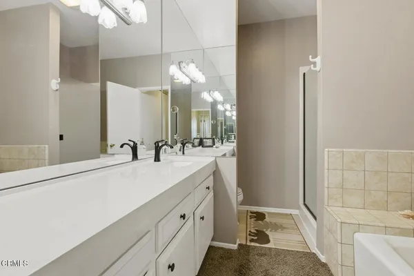 a bathroom with a tub a double vanity sink and mirror
