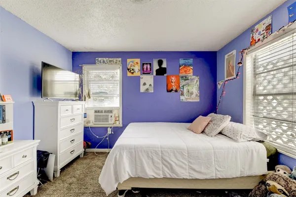 a bedroom with a bed and a flat tv screen on dresser