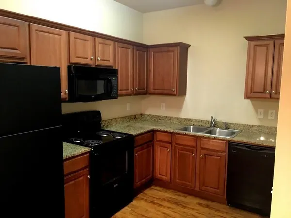 a kitchen with granite countertop wooden cabinets stainless steel appliances and a sink
