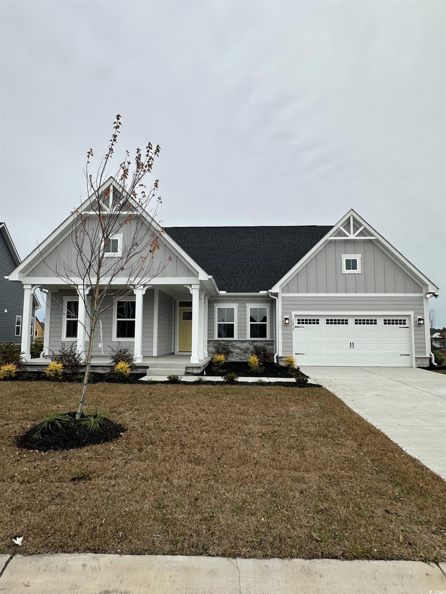 7015 Denim Loop Myrtle Beach, SC 29579 - Photo 1 of 1 Craftsman-style house featuring a porch, board and batten siding, concrete driveway, a shingled roof, and a front yard