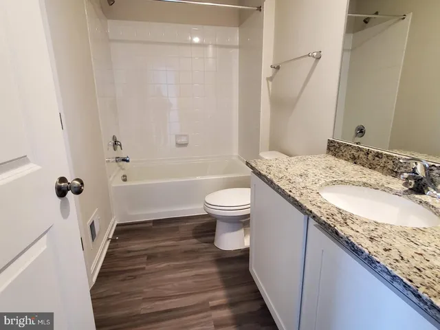 a bathroom with a granite countertop sink a toilet a mirror and shower