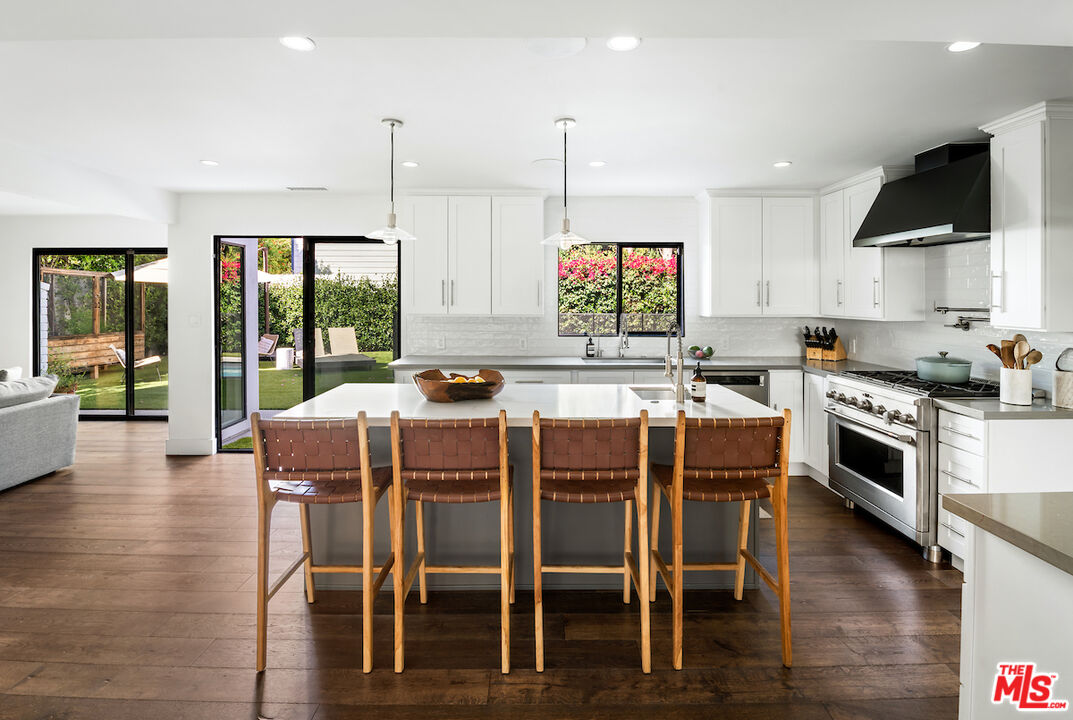17003 Rancho Street Encino, CA 91316 - Photo 12 of 29 a kitchen with stainless steel appliances granite countertop a stove top oven a sink a dining table and chairs with wooden floor