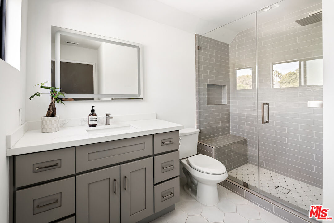 17003 Rancho Street Encino, CA 91316 - Photo 26 of 29 a bathroom with a toilet a sink a glass door a shower a and mirror