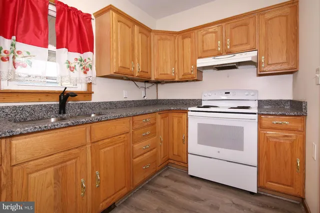 a kitchen with granite countertop wooden cabinets stainless steel appliances and a sink