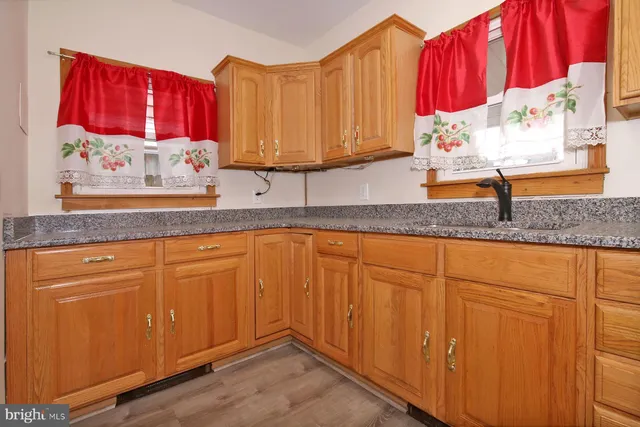 a kitchen with granite countertop a sink a window and cabinets