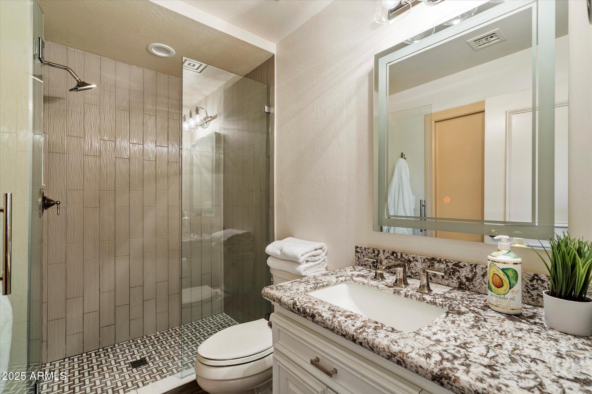 10801 East Happy Valley Road, Unit 133 Scottsdale, AZ 85255 - Photo 37 of 75 a bathroom with a granite countertop sink toilet a large mirror a shower and a bathtub