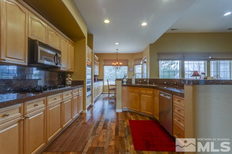 5265 North Elk River Road Reno, NV 89511 - Photo 6 of 25 a kitchen with stainless steel appliances granite countertop a stove a sink dishwasher and a microwave oven with wooden floor