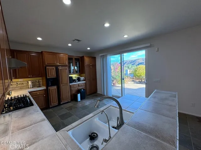 a large kitchen with stainless steel appliances granite countertop a stove a sink and a microwave