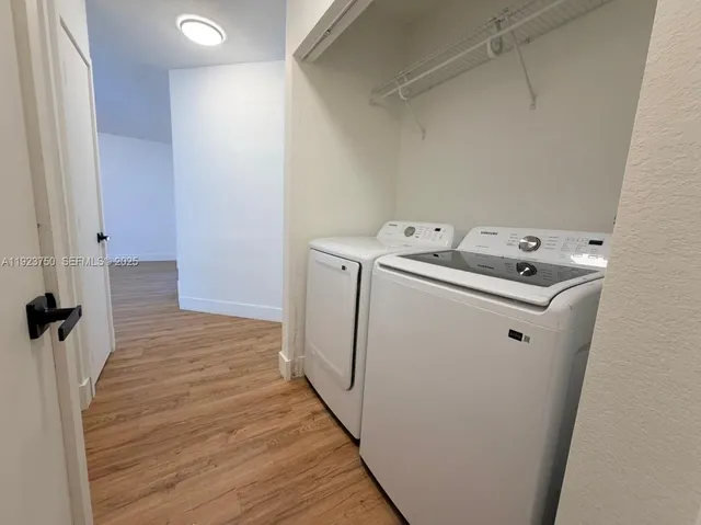 a utility room with wooden floor washer and dryer