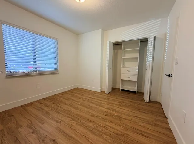 a view of an empty room with closet and a window