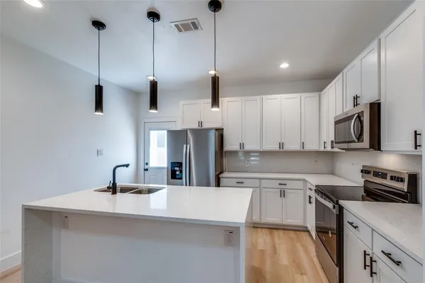 a kitchen with stainless steel appliances granite countertop a sink a stove and a refrigerator