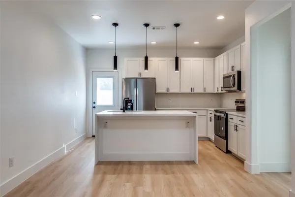a large white kitchen with stainless steel appliances