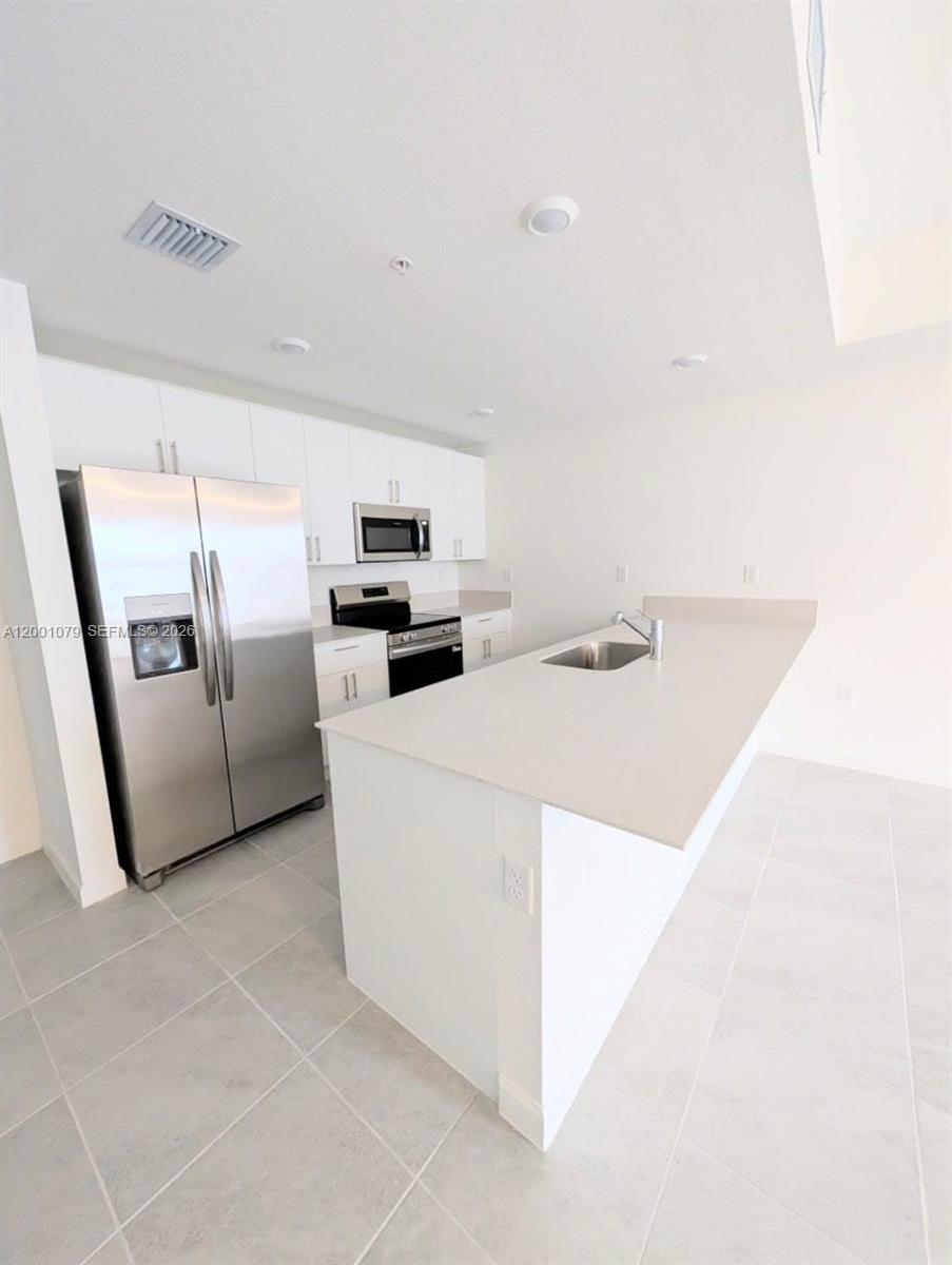 12476 Southwest 248th Street, Unit 5 Homestead, FL 33032 - Photo 5 of 10 a kitchen with stainless steel appliances a refrigerator sink and microwave