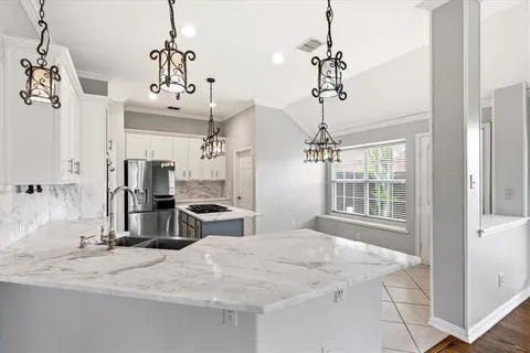 a view of a kitchen with kitchen island a sink and a chandelier